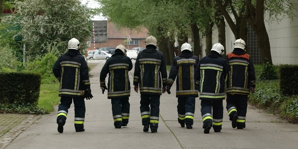 Brandweermannen lopen op een rijtje